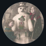 Sticker Rond Photo de Christmas Girls et Snowman Vintage<br><div class="desc">Une charmante carte postale de Noël 1910 française de deux jolies et adorables petites filles qui s'embrassent et posent avec leur ami bonhomme de neige festif,  alors que la neige flotte sur elles.</div>