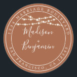 Sticker Rond Rustic Lights TerraCotta Mariage Adresse de retour<br><div class="desc">Mariage moderne et chic, le nom d'adresse de retour avec vos noms en blanc élégant script manuscrit sur un arrière - plan en terre cuite avec une touche élégante de lampes à cordes rustiques de fées. Ajoutez simplement vos noms et votre adresse. Conçu exclusivement pour vous par Happy Dolphin Studio....</div>