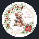 Sticker Rond Teddy Bear Foliage Poinsettia Bébé 1er Noël<br><div class="desc">Ce design présente un ours en peluche de Noël avec chapeau de Père Noël et présente à l'intérieur de la couronne de Noël avec poinsettia,  feuillage verdoyant et baies rouges. Vous pouvez ajuster le texte en fonction de vos besoins.</div>