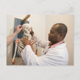 Studentenartsen bestuderen anatomie op een skelet briefkaart