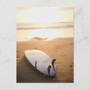 Surfbord op strand bij zonsondergang briefkaart