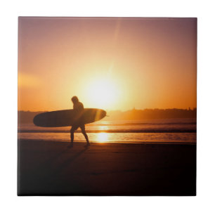 Surfer op strand bij zonsondergang tegeltje