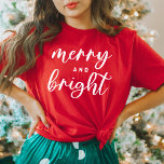 T-shirt Joyeux et brillant Noël des femmes rouges modernes<br><div class="desc">Un tee-shirt graphique festif pour les femmes avec une typographie en minuscules moderne avec "Joyeux et brillant". Le texte blanc et le style de t-shirt rouge peuvent tous deux être modifiés.</div>