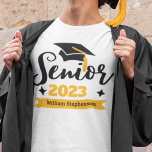 T-shirt Nom de l'année d'obtention du diplôme de la classe<br><div class="desc">Célébrez votre année de troisième année et de graduation avec ce t-shirt moderne avec une typographie contemporaine "Senior 20xx" en noir et or décoré avec un casquette noir diplômé avec un goût doré; customisez facilement ce t-shirt avec votre année de graduation et votre nom en éditant les champs modèles. Ce...</div>