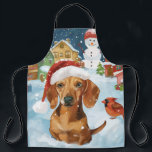 Tablier Dachshund Winter Wonderland Christmas Joy<br><div class="desc">Ce design festif reflète l'esprit joyeux de la période des fêtes, avec un adorable petit portant un chapeau de Père Noël. Le chien est niché dans un pays des merveilles hivernales, avec un bonhomme de neige, un sapin de Noël décoré et des cadeaux joliment emballés. Les flocons de neige tombent...</div>