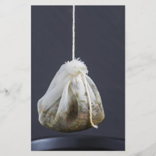 Thee zakje hangt in een kopje briefpapier