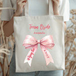 Tote Bag Elle noue le nœud rose Team Mariée<br><div class="desc">Décoré avec un nœud de couleur rose. Personnalisez et ajoutez un nom.
Texte : Team Mariée. Elle noue le nœud.</div>