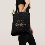 Tote Bag Nom de monogramme pailleté or noir élégant<br><div class="desc">Un fond noir élégant. Personnalisez et ajoutez votre nom,  initiales de monogramme. Votre monogramme en tant que motif de fond. Le nom est écrit avec un style de lettrage manuscrit. Lettres blanches et dorées.</div>
