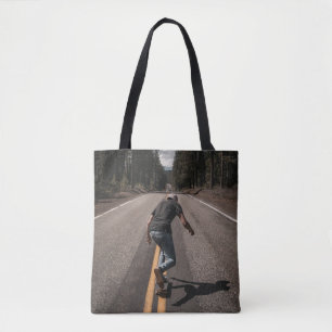 Tote Bag Un homme joue au skateboard sur la route le matin