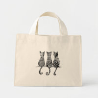 Trois chats noirs et blancs sur un sac