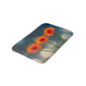 Trois Gerberas orange dans un tapis de bain de ran (Angle)