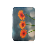 Trois Gerberas orange dans un tapis de bain de ran (Devant (Vertical))