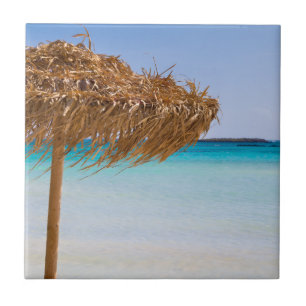Tropisch strand met strooien parasol tegeltje