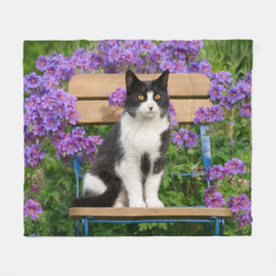 Tuxedo-kat op een tuinstoel met bloemen fleece deken