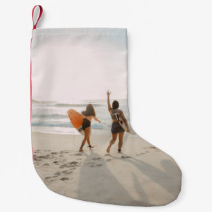 Twee vrouwen lopen naar de oceaan met surfen kleine kerstsok
