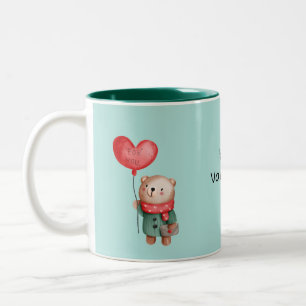 Valentijnsdag teddy - beer houdt liefdesballon aan tweekleurige koffiemok