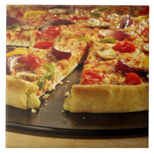 Vegetable pizza gesneden op zwarte pan op hout tegeltje