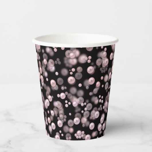 Verspreiding van roze en witte parels op zwarte ve papieren bekers (Voorkant)