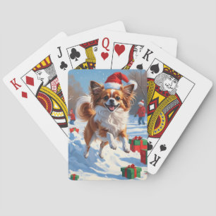 Vlindervlindhond loopt in de sneeuw met kerstmuts pokerkaarten