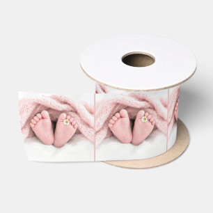 Voetjes van een babymeisje met een witte madeliefj lint