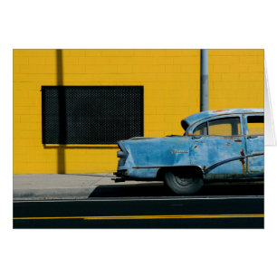 Voiture bleu rouillé et mur jaune