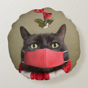 Vrolijk kerstkat in gezichtsmasker onder mistletoe rond kussen