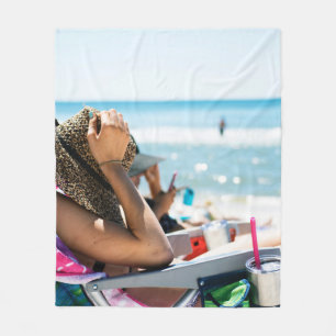 Vrouw die op zonlounger ligt en haar gezicht bedek fleece deken