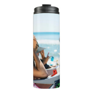 Vrouw die op zonlounger ligt en haar gezicht bedek thermosbeker