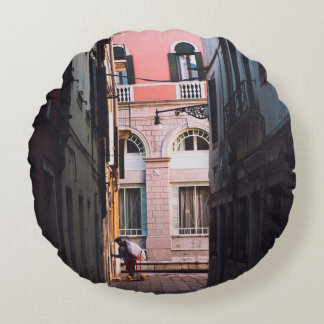 VROUW IN WITTE SHIRT EN ZWARTE PANTEN KWAMEN OP SI ROND KUSSEN