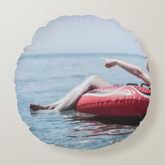 Vrouw op een opblaasbare drijver in de oceaan geri rond kussen