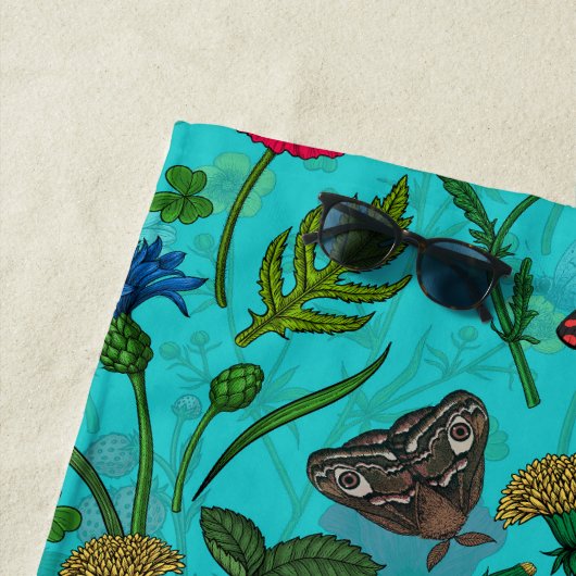 Wilde bloemen en motten op blauwgroen strandlaken (In situ)