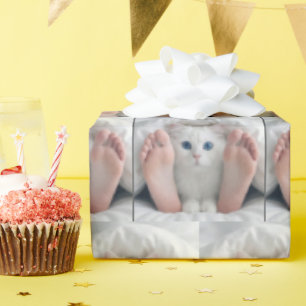Witte kat en menselijke voeten onder een dekbed cadeaupapier