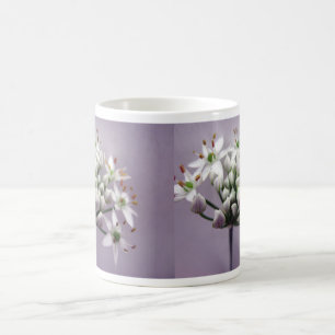 Witte knoflookbiesbloemen op paars koffiemok
