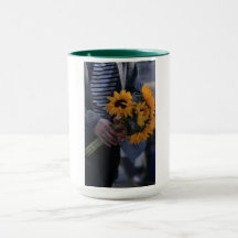 Witte mok waar een hand zonnebloemen vasthoudt met