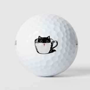 Zwart katje met rode neus verstopt in een kopje golfballen