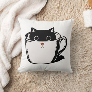 Zwart katje met rode neus verstopt in een kopje kussen