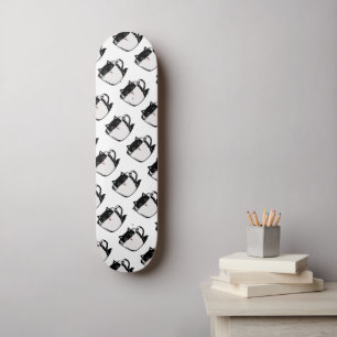 Zwart katje met rode neus verstopt in een kopje skateboard