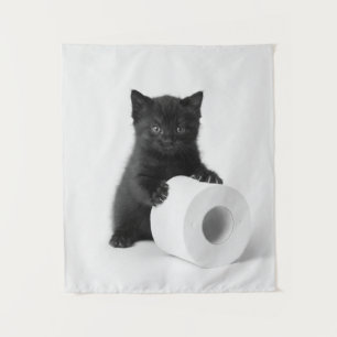 Zwarte babykatje bewaakt rol toiletpapier op wandkleed