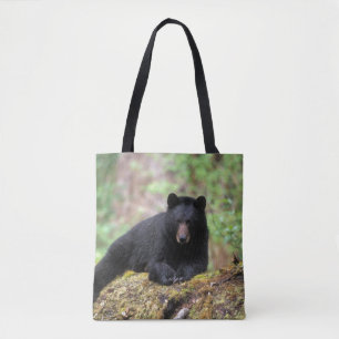 Zwarte beer op een oude boomstam in de tote bag