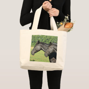 Zwarte paarden in een zonovergoten wei grote tote bag